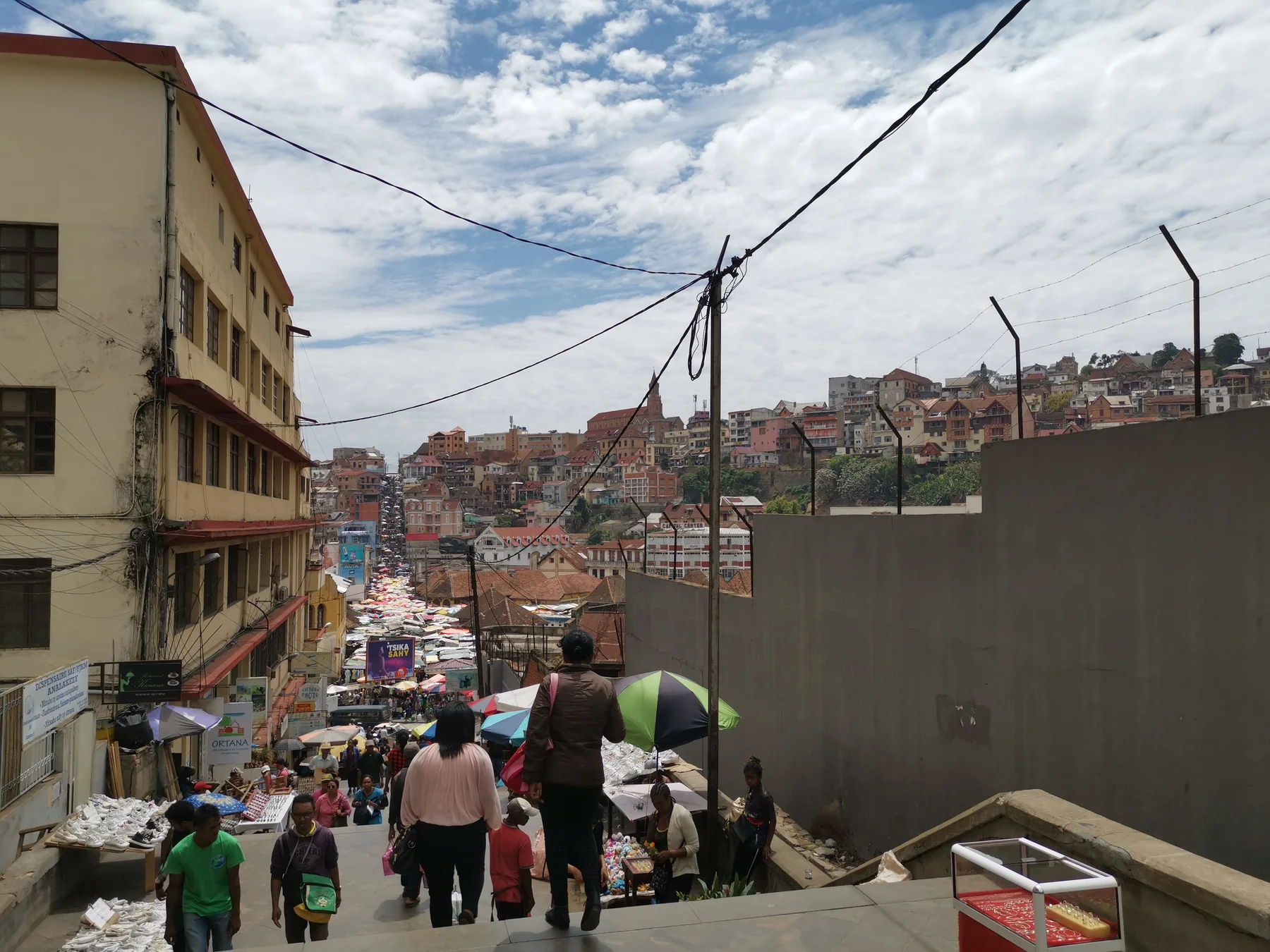 People walking down a market stairway with Antananarivo beyond
